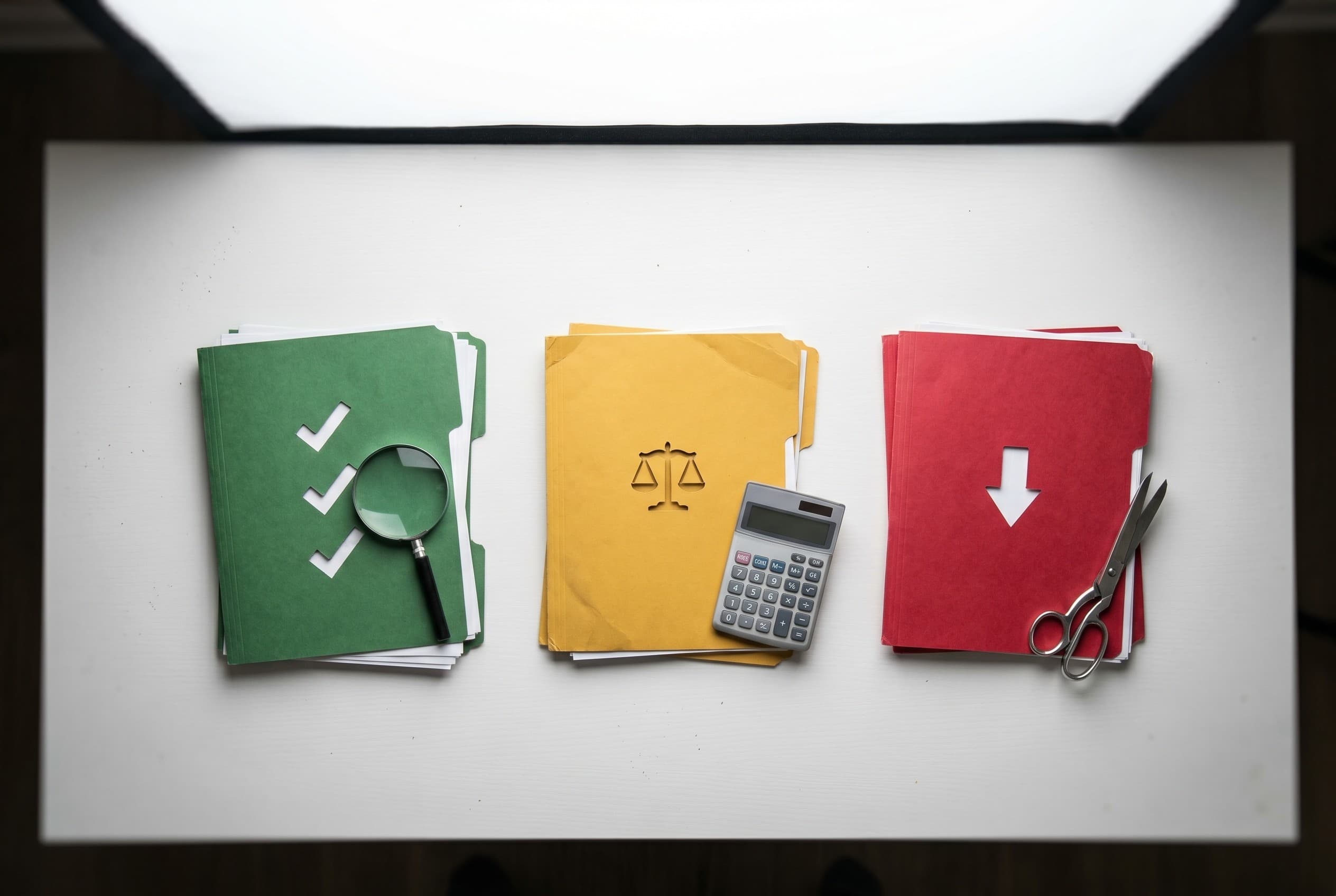 Top-down flat-lay photo on a clean white desk showing three distinct paper stacks arranged left to right to compare debt solu