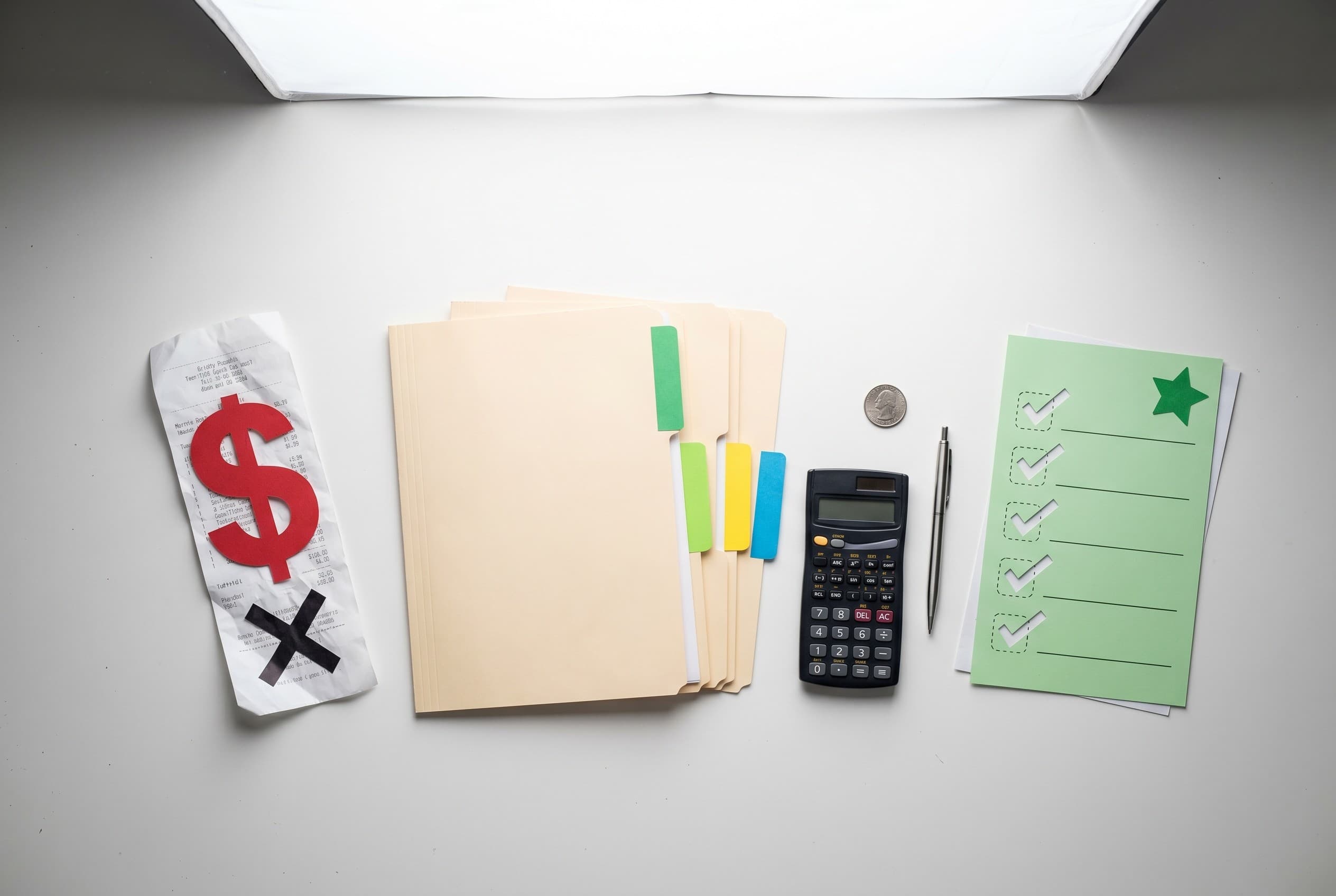 Top-down flat-lay photo on a clean white desk showing credit repair pricing concept. On the left, a red paper cutout dollar s