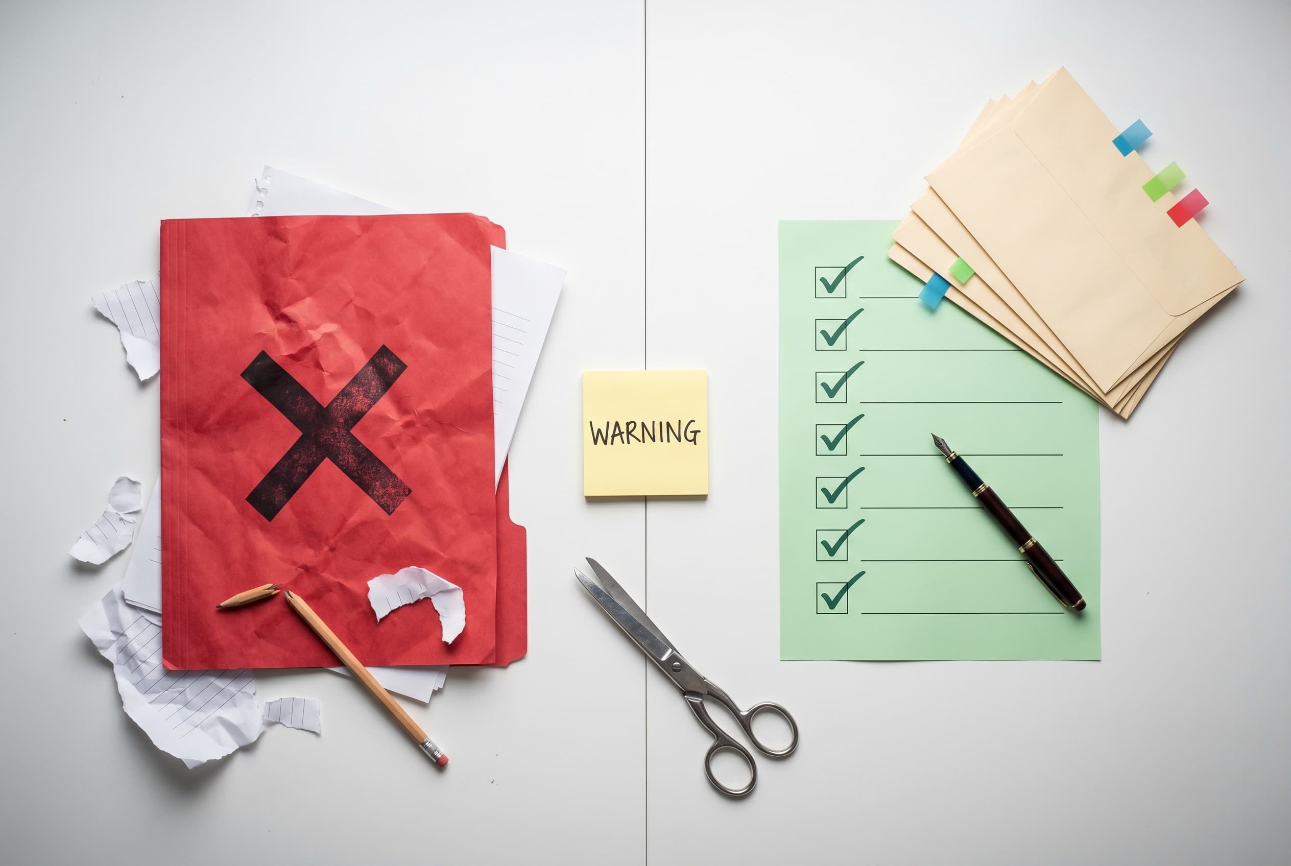 Top-down flat-lay photo of a clean white desk split into two halves. On the left, a crumpled red folder stamped with a large