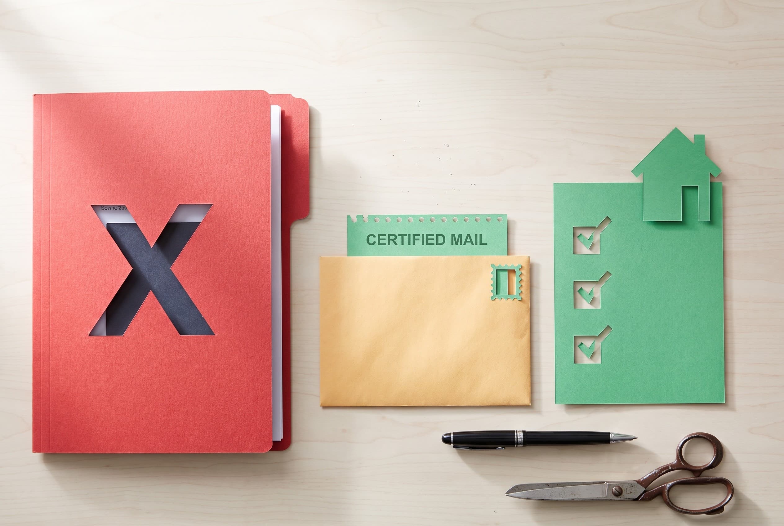 Top-down flat-lay photo on a clean light-wood desk. On the left, a red folder with a bold stamped X cutout representing a dis