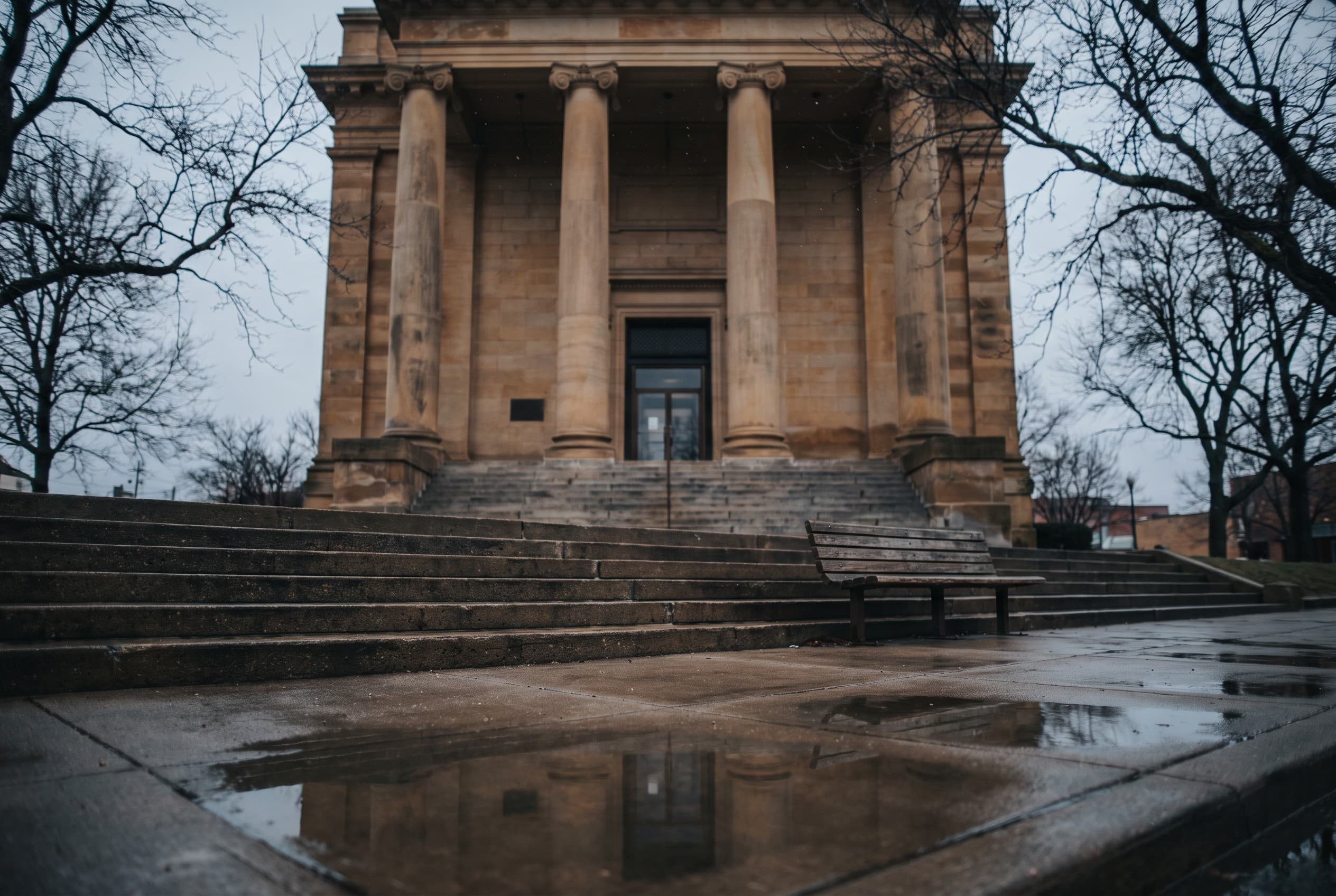 The exterior of a typical American county courthouse on an overcast morning, shot from street level looking up the stone step