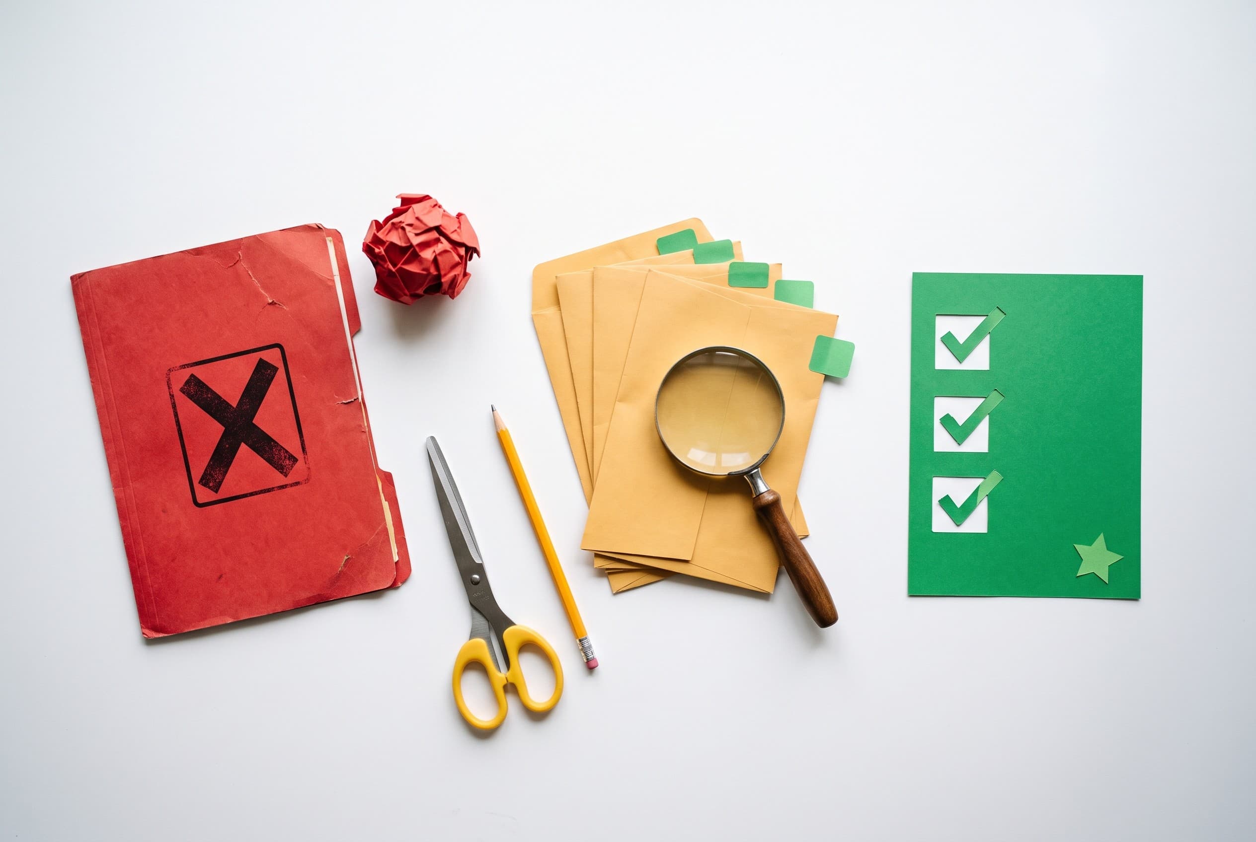Top-down flat-lay photo on a clean white desk showing two paths of paper cutouts. On the left, a red folder stamped with a bo