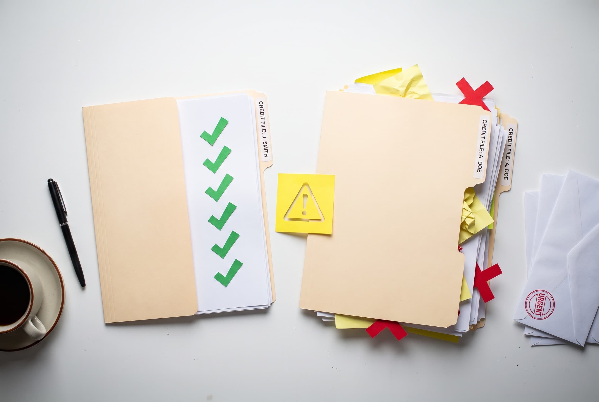 Top-down flat-lay photo on a clean white desk showing two side-by-side manila folders representing two people's credit files.